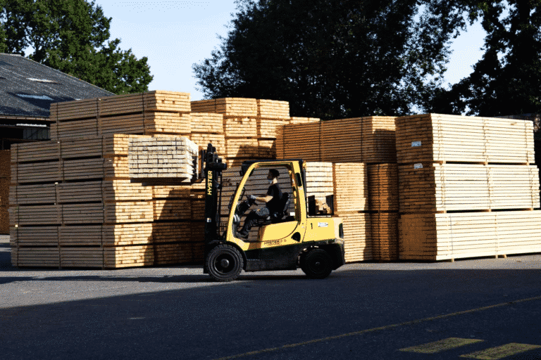 Stuwhout wordt vervoerd door een pick up. Grote stock stuwhout op de achtergrond